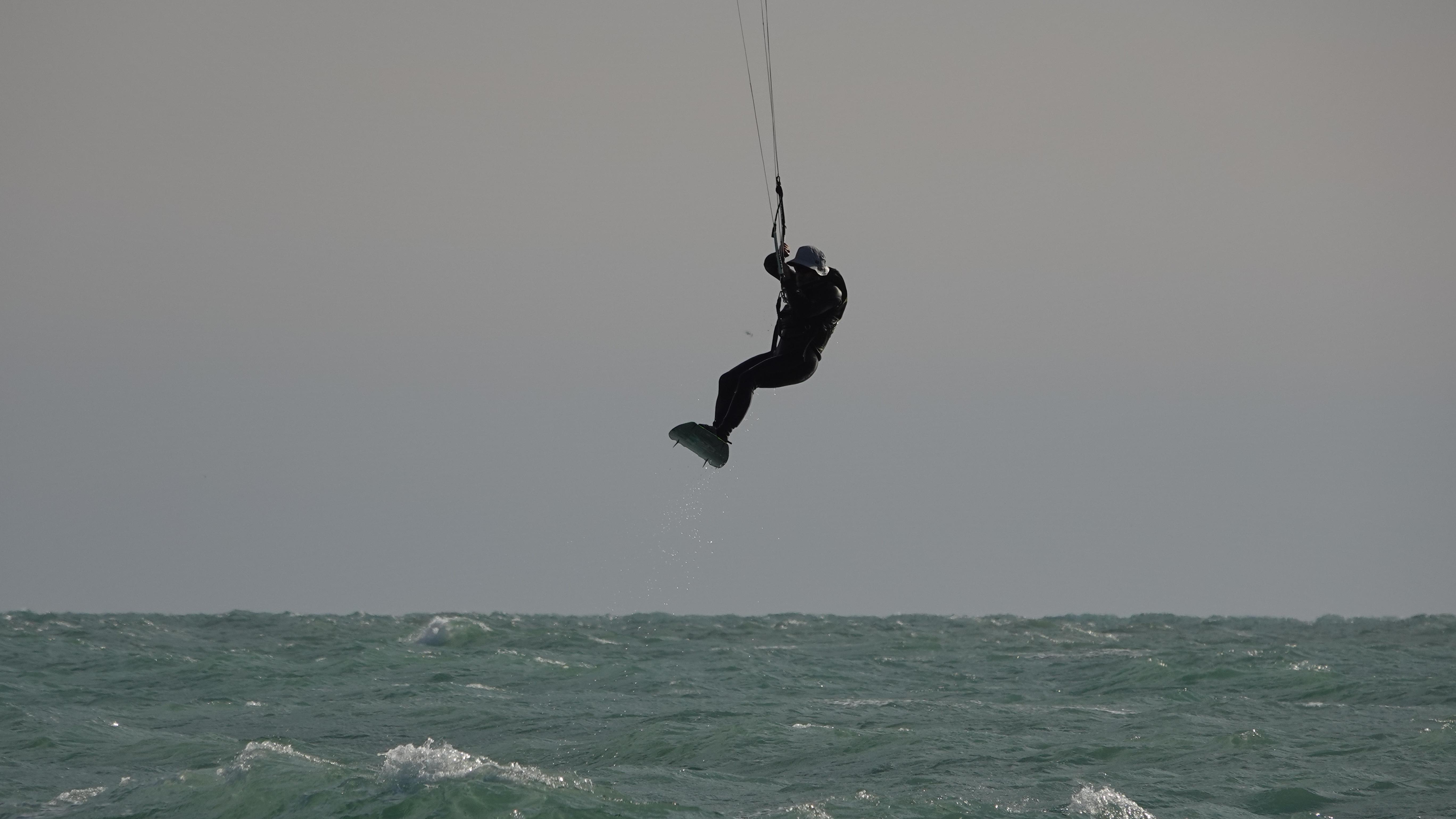 Dramatic silhouette of kiteboarder against moody sky
