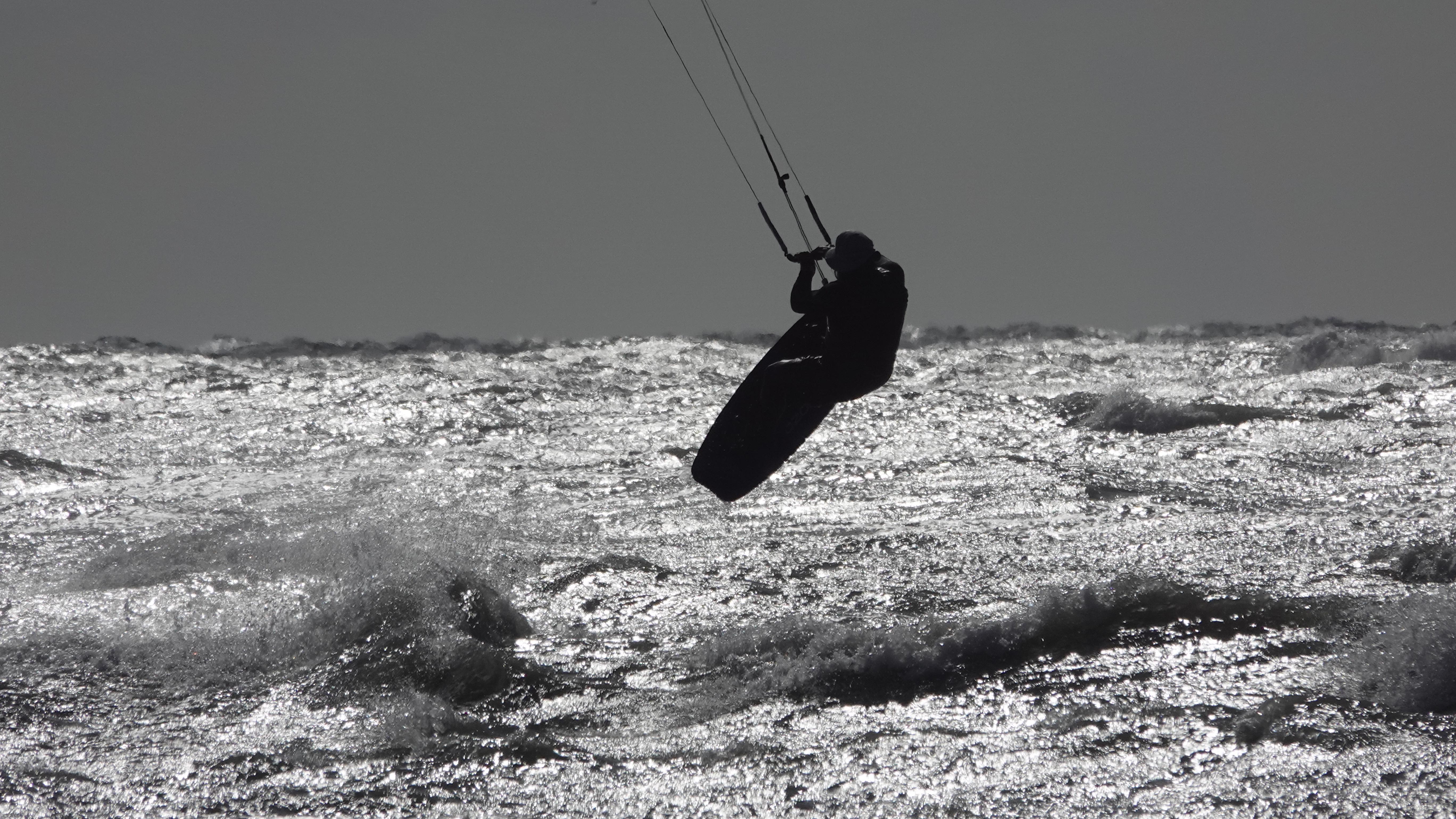 Black and white artistic shot of kiteboarder in mid-air