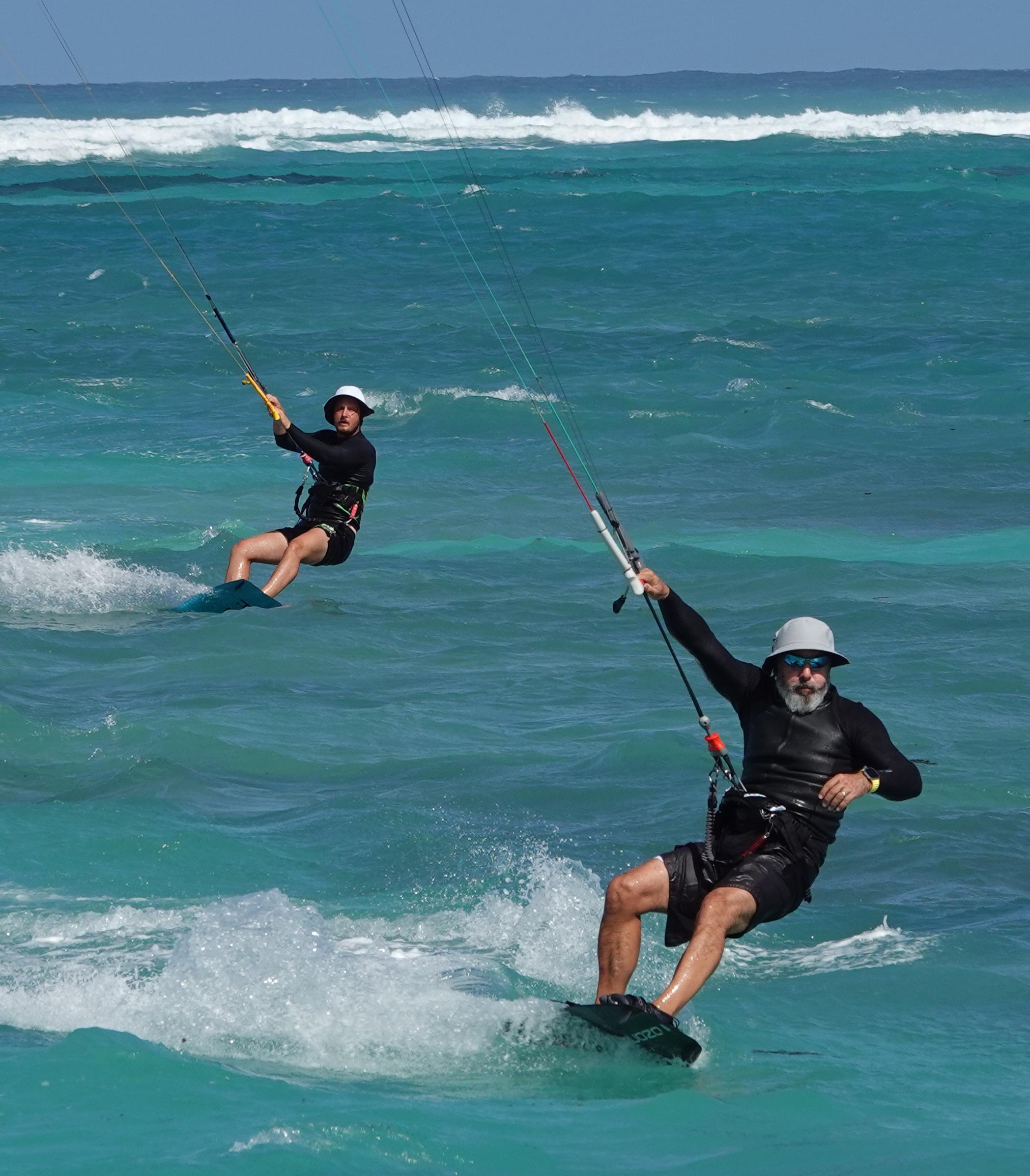 Benny and Izzy kiteboarding together in turquoise waters
