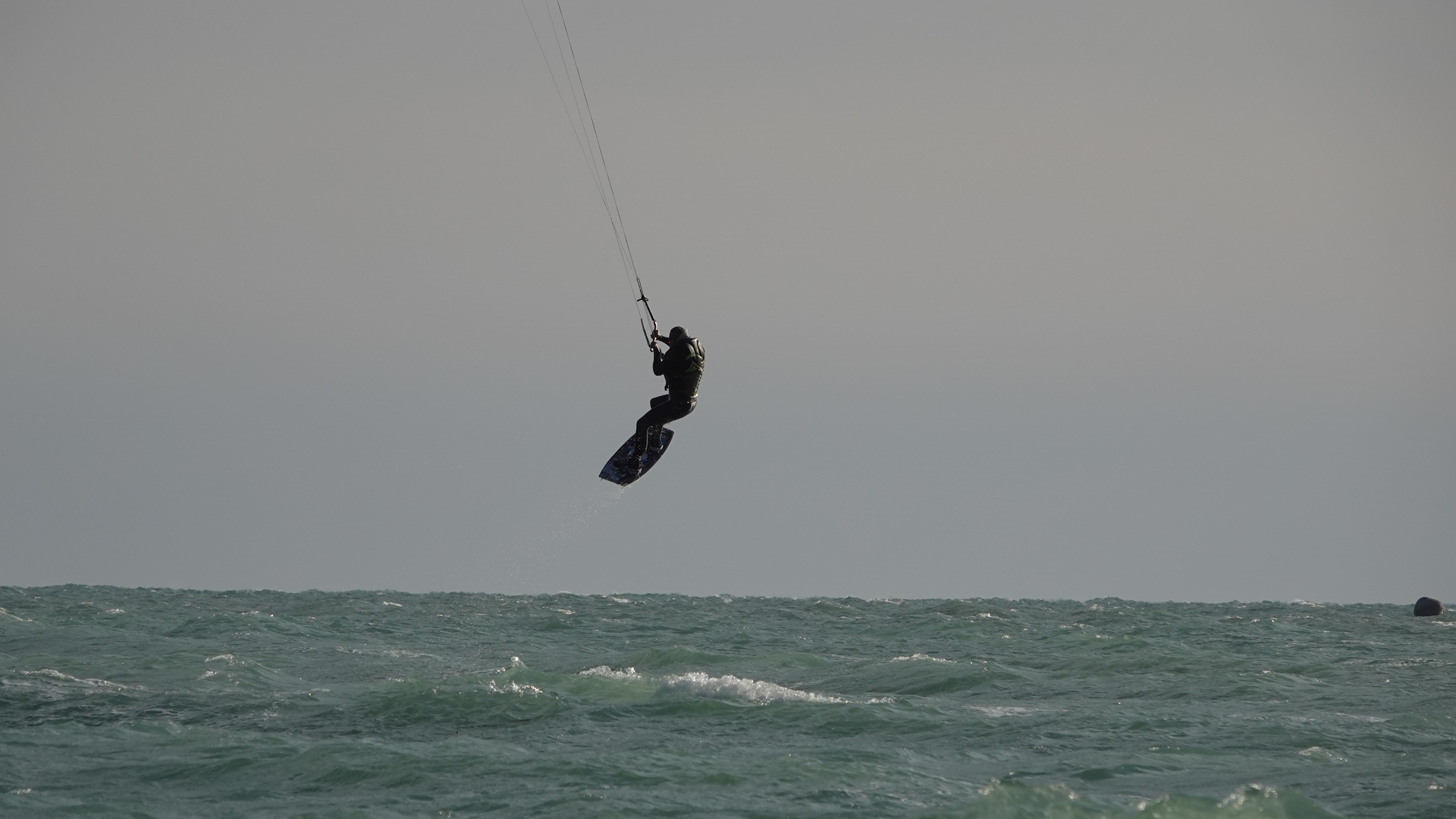 Spectacular high-altitude kiteboarding jump against gray sky