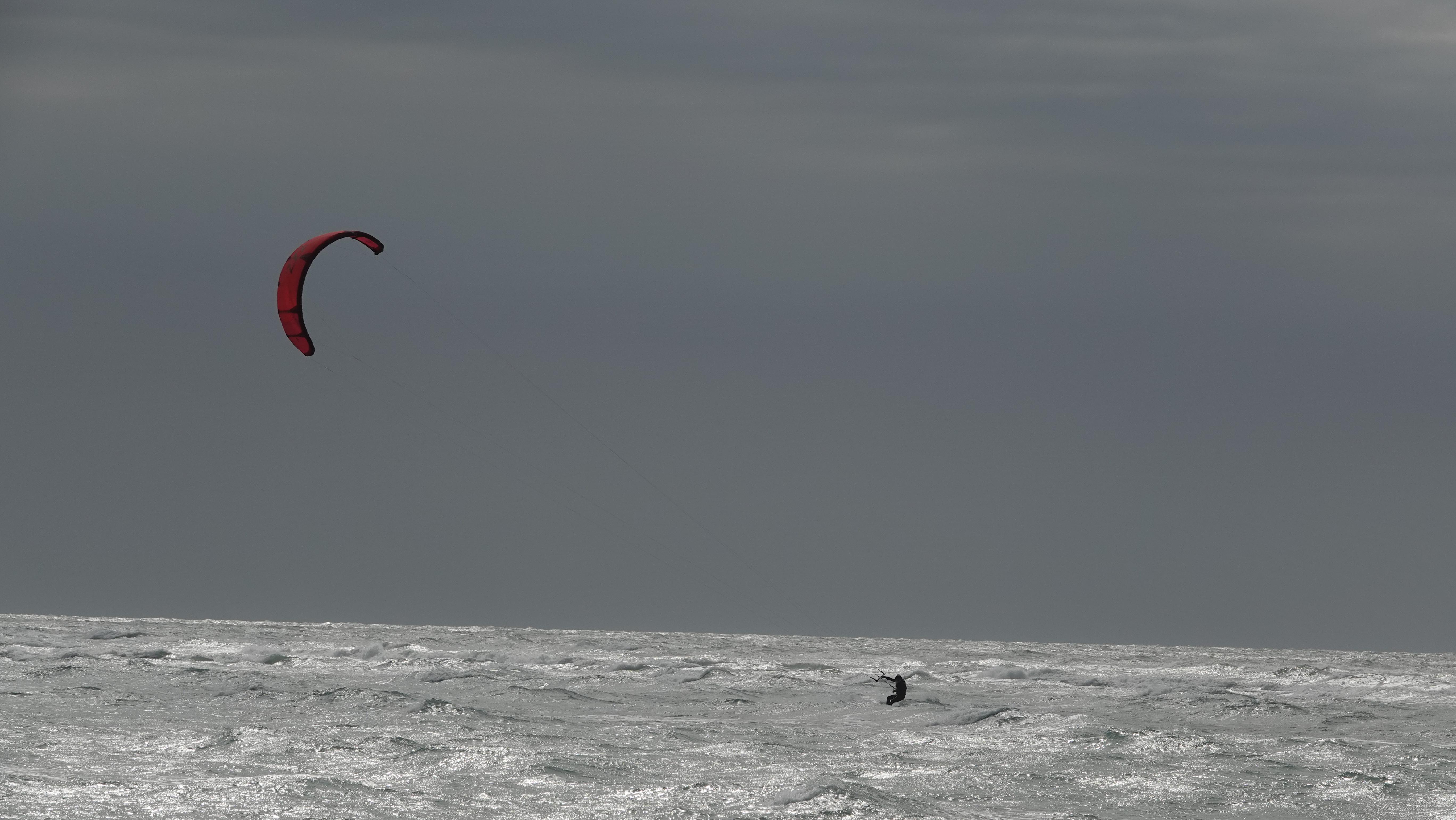 Moody atmospheric shot with red kite over gray ocean
