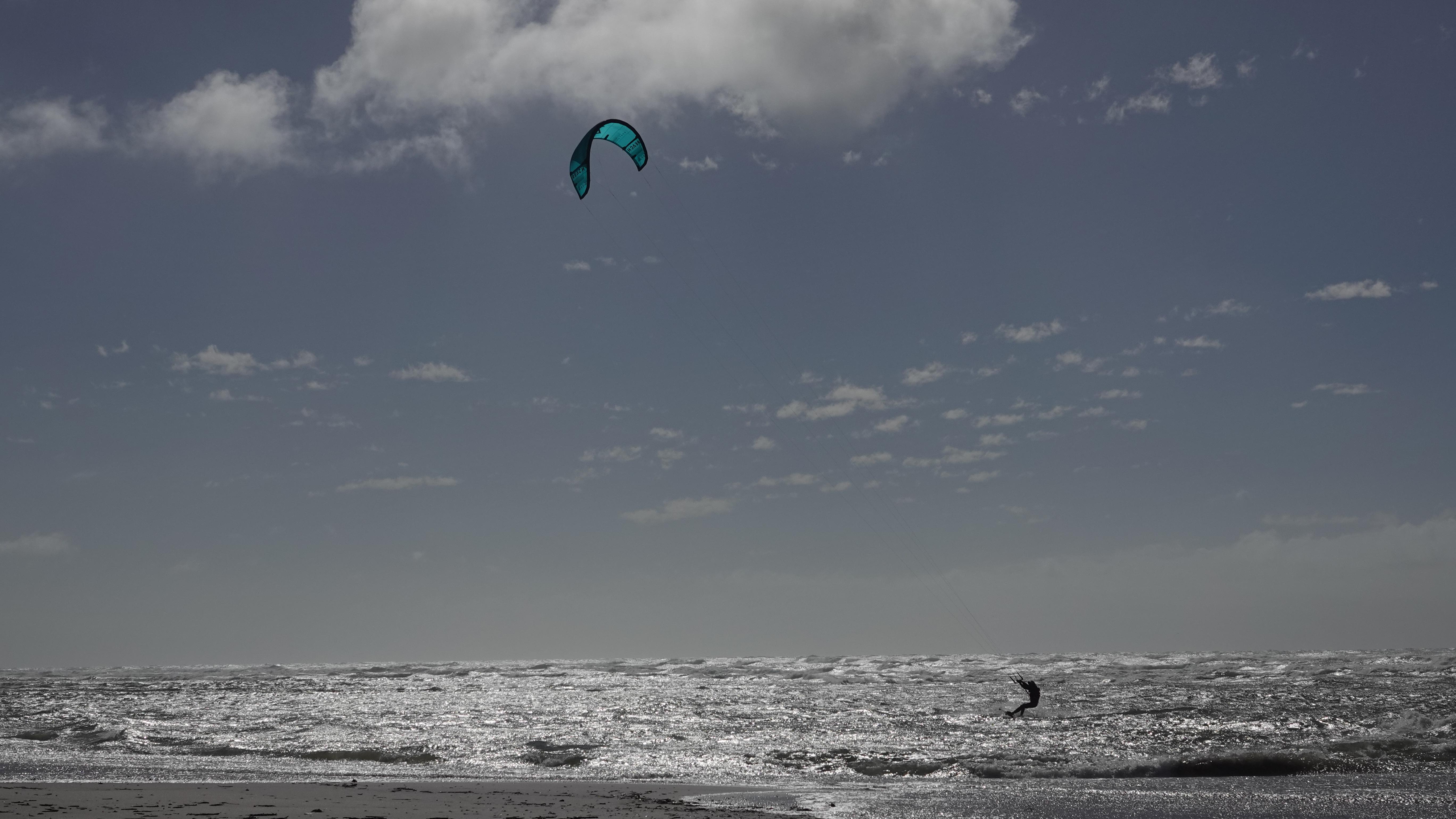 Scenic shot with turquoise kite against dramatic cloudy sky